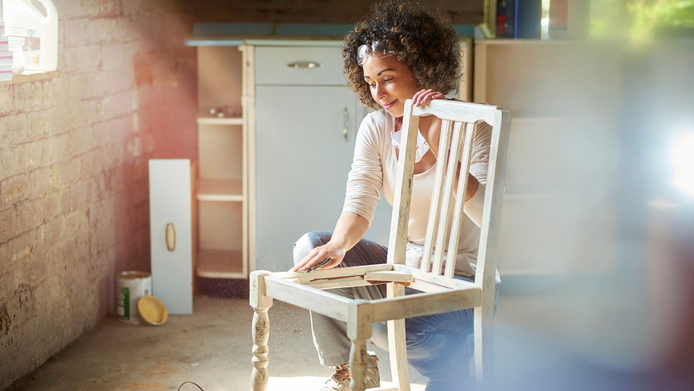 a woman restores and improves an old wooden chair in her workshop